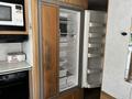 Interior view of a 2000 Ford Motorhome showing a refrigerator with shelves and compartments open to reveal empty storage space