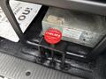 A red circular button labeled PTO CONTROL CHLESA mounted on a black bracket in a vehicle's interior with a textured surface beneath it