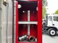 A metal compartment of a fire truck displaying hoses and connectors used for firefighting equipment