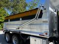A silver 2005 Volvo VND 122 dump truck with a yellow and black dump bed and hydraulic lift arm on the side