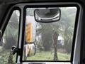 A 2016 International 7400 truck's interior side view showing the driver's side mirror and rearview mirror with rain droplets on the glass