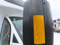 A 2020 Chevrolet Express van with a black side mirror featuring an orange reflective strip