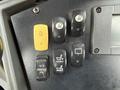 Close-up of a control panel featuring several switches including a yellow button and various black buttons for functions like lights and seat adjustments