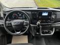 The interior dashboard of a 2021 Ford Transit featuring a steering wheel a digital display and a central touchscreen with various controls and buttons