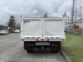 A white 2014 Hino 195 truck with a flatbed and double doors at the rear parked on a street