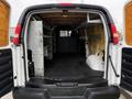 The image shows the open back of a 2014 GMC Savana van with shelving units on one side and a spacious cargo area visible