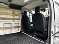 Interior of a 2023 Ford Transit showing two black seats and wooden shelving against a white panel van wall