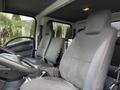 Interior of a 2015 Isuzu NPR HD featuring two front seats with fabric upholstery and a steering wheel visible in the foreground