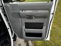 The interior door panel of a 2011 Ford Econoline featuring a gray armrest a handle and storage compartments