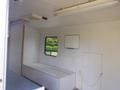 Interior of a 2004 Royal 18 Foot Office Trailer featuring a long bench seating area a small wall-mounted screen and a window