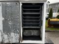 An open compartment of a 2009 Ford F-550 showing multiple shelves inside with a weathered and rusty interior