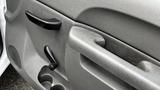 The interior door panel of a 2013 Chevrolet Silverado 1500 featuring a textured gray surface door handle and a pull lever with cup holder compartments below