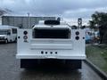 A white 2014 Ford F-350 SD with a flatbed and rear access doors is parked with its back facing the viewer