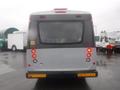 A rear view of a 2016 Chevrolet Express bus with red taillights and a warning sign on the back door