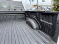 A 2018 Ford F-150 truck bed with a textured black surface and a wheel well protruding from the side