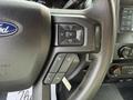 Close-up of the steering wheel controls of a 2020 Ford F-550 featuring audio volume buttons and a menu navigation button