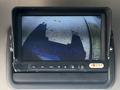 A monitor displaying a camera feed showing the rear view of a 2004 Freightliner M2 truck with a shadow cast on the surface below