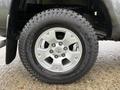 A close-up of a silver wheel and tire on a 2015 Toyota Tacoma showcasing the rim design and tread pattern of the tire