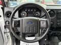 The interior of a 2015 Ford F-350 SD featuring a black steering wheel with a Ford logo and various controls on the dashboard and center console