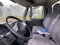 The interior of a 2014 International Durastar truck features a steering wheel and a row of gray seats with seatbelts and scattered papers on the seat