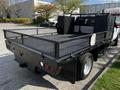 A 2016 Ford F-550 truck with a flatbed and metal mesh sides featuring a black finish and various storage compartments on the rear