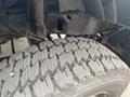 Close-up of the tire tread on a 2003 Ford F-450 SD showing detailed grooves and patterns with part of the vehicle's suspension visible in the background
