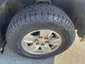 A 2015 Chevrolet Silverado 1500 tire with rugged tread design and a silver alloy wheel