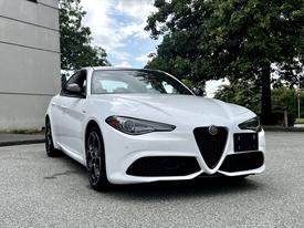 A white 2023 Alfa Romeo Giulia with a sleek design features a distinctive front grille and sporty alloy wheels