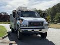 2009 GMC C5500 with a chrome front grille and multiple orange roof lights parked with its body painted white and equipped for utility services