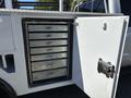 A 2016 Ford F-550 with an open cabinet door revealing six metal drawers arranged vertically inside the compartment