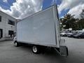 A 2018 Isuzu NPR box truck with a large, plain white cargo area and visible wheels, positioned at a slight angle