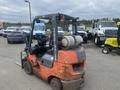 A red 2010 Toyota 7FGGU25 forklift with a propane tank attached on the back and visible wear on its body