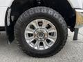 A close-up of a silver wheel and tire on a 2020 Ford F-350 featuring a rugged tread pattern and chrome accents on the wheel rim
