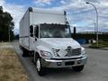 A white 2006 Hino 268 box truck with a diamond plate front grille and amber clearance lights parked on a street