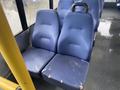 A pair of worn blue bus seats with visible fraying and damage, positioned next to a vertical yellow pole