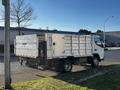 A 2014 Mitsubishi Fuso FE truck with a flatbed and metal side panels is parked on a street