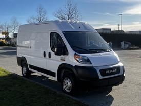 A 2021 RAM Promaster van in white with a black front grille and side panels parked on a paved surface