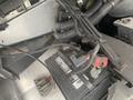 A 2012 Ford Econoline's battery with connected wires and terminals visible in the engine compartment