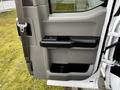 The interior door panel of a 2016 Ford F-150 featuring a gray finish with a black armrest and a small window control button