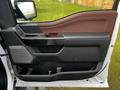 Interior door panel of a 2021 Ford F-150 featuring brown and black materials with a speaker and handle