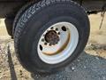 A close-up of a white rim with a rusty central hub and a large tire with a tread pattern mounted on a 2013 International 4300 truck