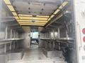 Interior view of a 2012 Ford Econoline cargo van showing two metal shelves on either side and a driver's area at the back