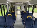 Interior of a 2015 Chevrolet Express showcasing blue seats with yellow armrests arranged in rows along the sides of the vehicle