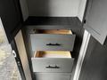 A cabinet from a 2022 Aspen Trail with two open wooden drawers and a shelf above them, featuring black handles