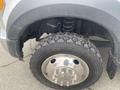 Close-up of the front wheel and suspension of a 2017 Ford F-550 showing a large tire with deep treads and a shiny chrome wheel rim