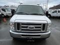 A 2014 Ford Econoline van with a silver exterior featuring a front grill and headlights visible with rain on the windshield