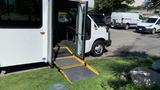 A 2011 Chevrolet Express with an open side door featuring a yellow wheelchair ramp extending outwards