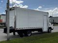 A 2018 Hino 195 box truck with a white exterior and a side door parked on the street