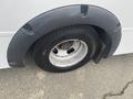 A close-up view of a Chevrolet Express wheel with a flat tire and a gray wheel arch attachment