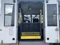 A 2016 Chevrolet Express with an open rear door showing a wheelchair lift with yellow safety barriers and a black metal platform